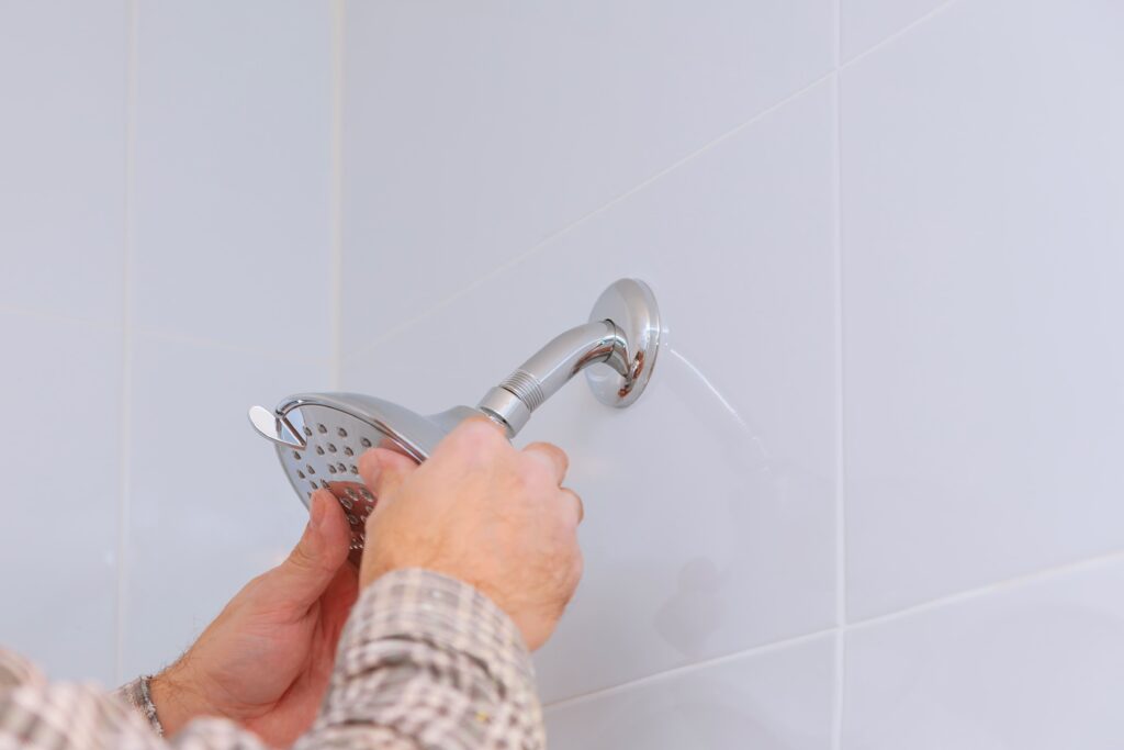 man installing shower head in bathroom remodel