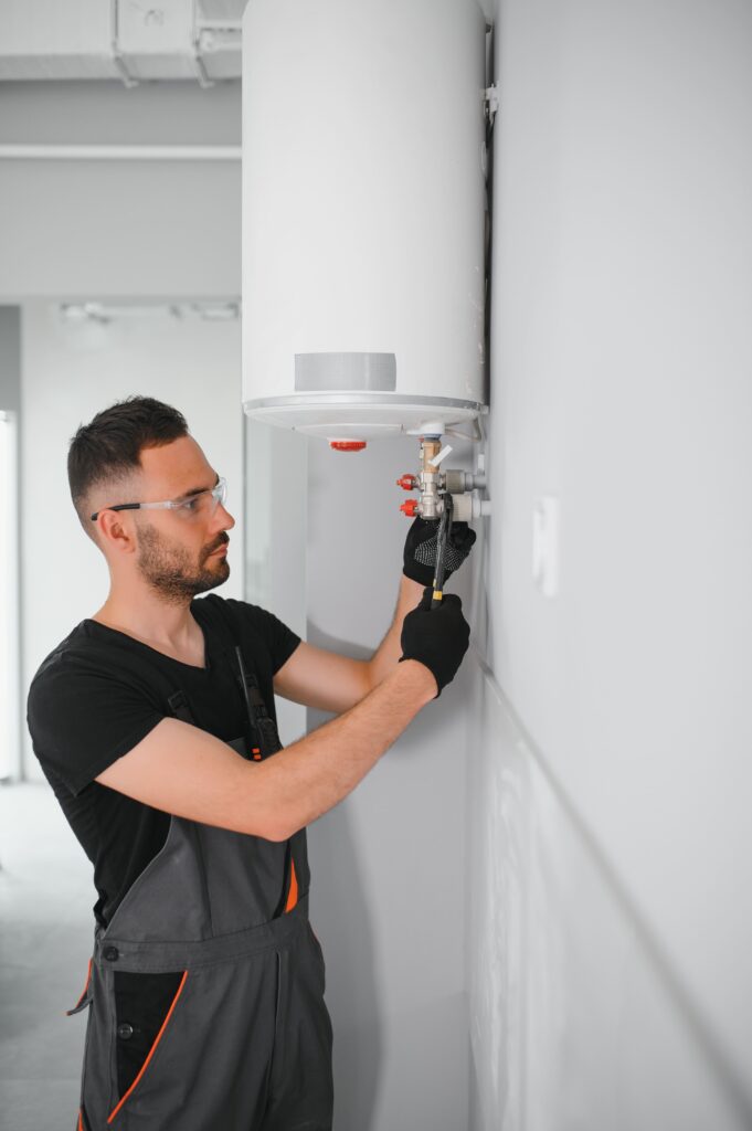 plumber in black and grey  installing a hot water system