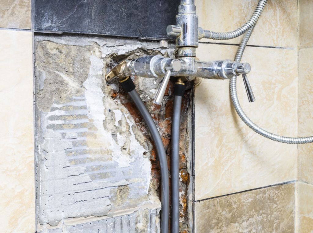 leaking pipes behind a tiled shower wall